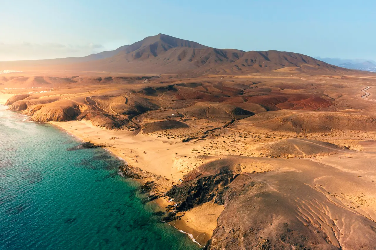 Strand und Vulkanberge auf Lanzarote aus der Luft