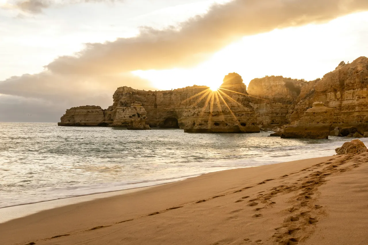 Strand mit Felsformationen an der Algarve bei Sonnenuntergang